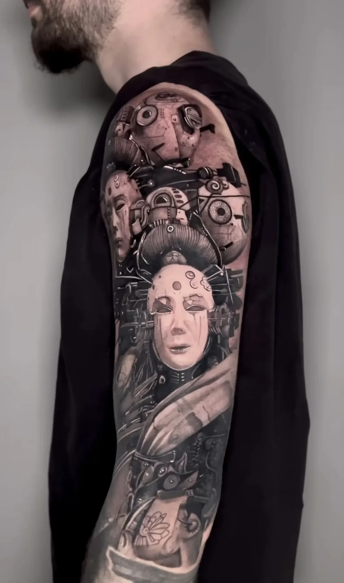 Black-and-Grey-Armtattoo von Ruby mit mechanischen Masken, Gesichtern und technischen Details
